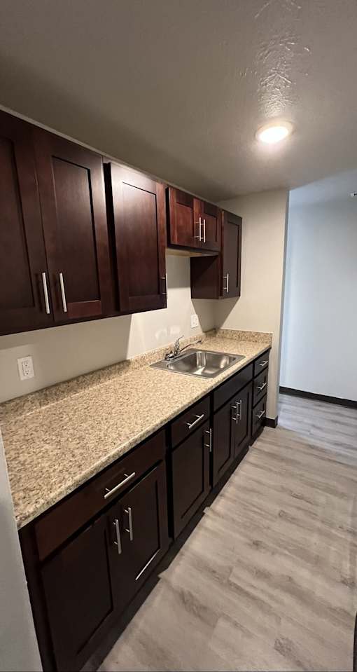 A kitchen with dark brown cabinets and a granite countertop.