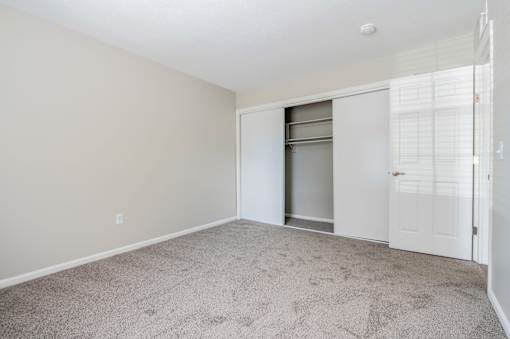 A room with a white door and a carpeted floor.