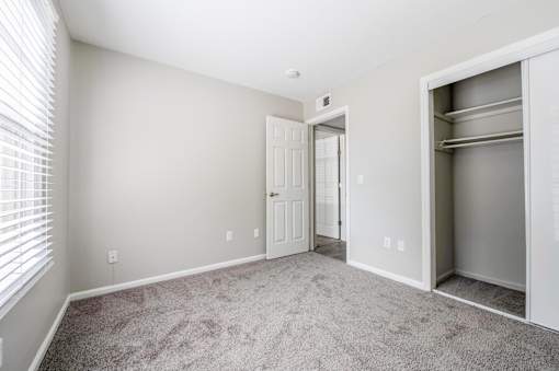 A room with a white door and a grey carpet.