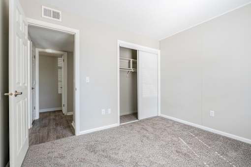 A room with a carpeted floor and two open doors.