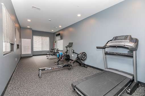 A home gym with a treadmill, rowing machine, and weights. at The Lumos Apartments, Cleveland