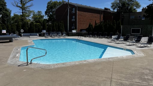 a swimming pool with chairs around it in front of a building at Heritage Apartments, Columbus, 43212