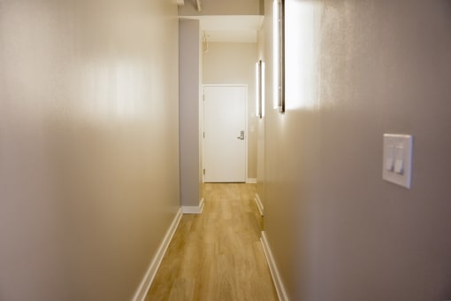 a hallway with wood floors and a white door