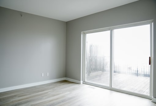 an empty room with a large window and wood floors