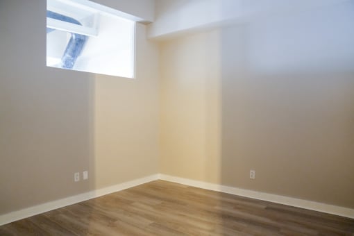 an empty room with a window and wooden floors