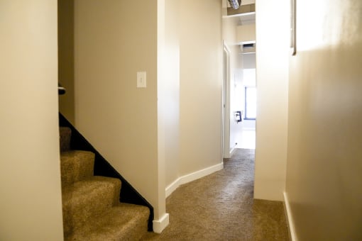 a hallway with carpeted stairs and white walls