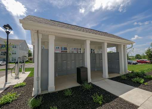 a kiosk with mailboxes and a trash can in front of a building at The Bend, Ohio, 43130