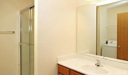 A bathroom with a sink, mirror, and shower.
