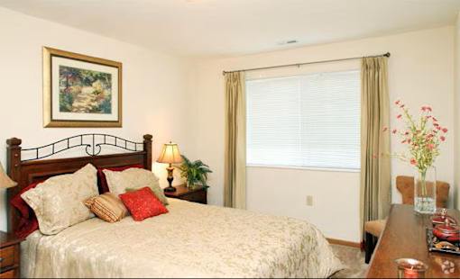 A bedroom with a bed, nightstand, and a painting on the wall.