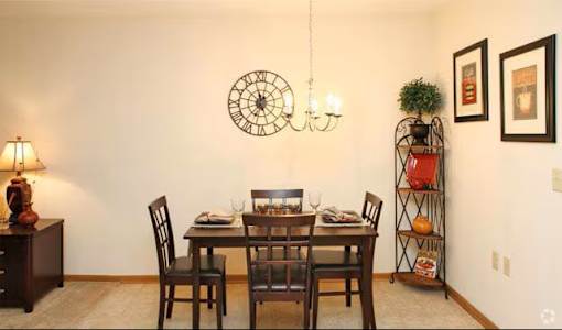 A dining room with a table set for two and a clock on the wall.