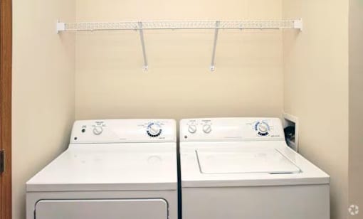 Two white front loading washing machines in a laundry room.