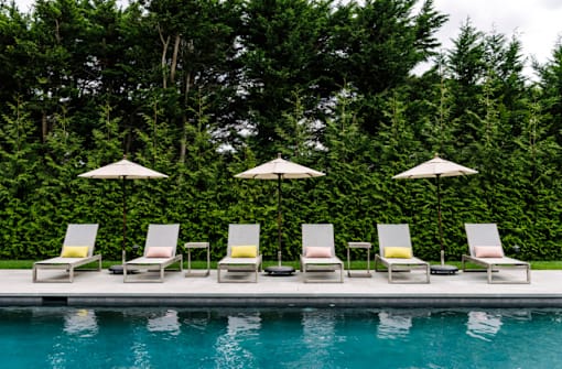 a row of lawn chairs and umbrellas next to a swimming pool