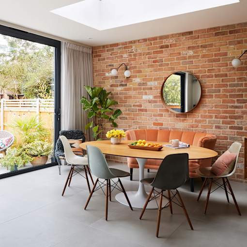 a dining area with a wooden table and chairs and a brick wall in the background