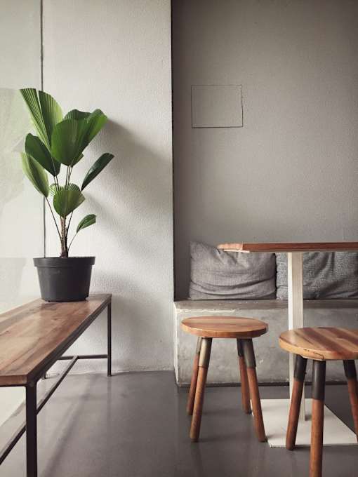 a table and three stools in a room with a plant and a bed