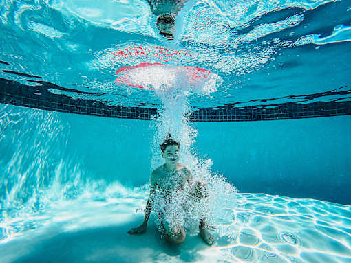 a boy is diving into a swimming pool