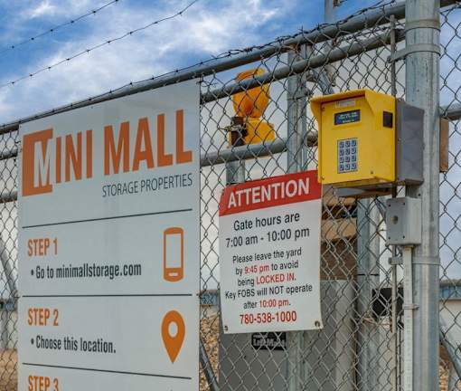 A sign for the Mini Mall Storage Properties is displayed on a fence.
