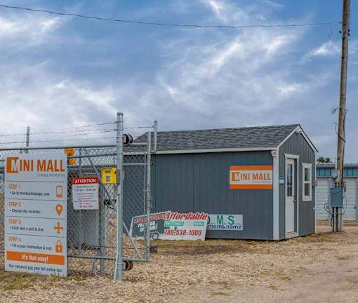 A sign for the Cini Mall is displayed in front of a small building.