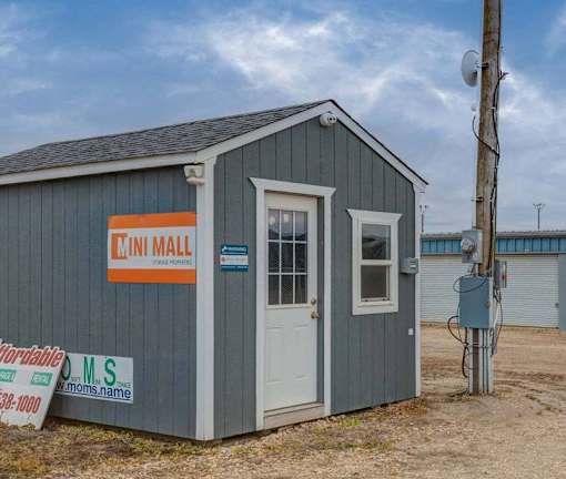 A small grey building with a white door and a sign that says "MINI MALL".