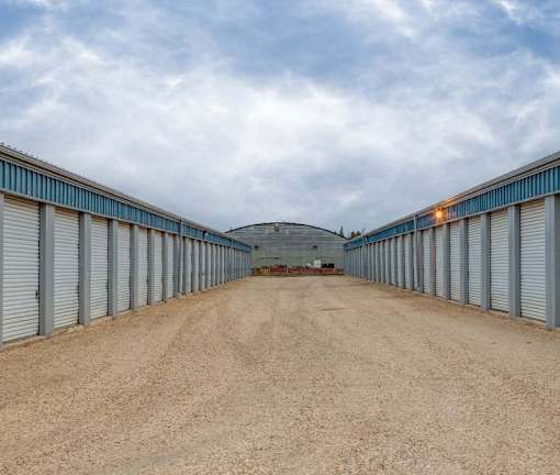 A long, narrow storage facility with a dirt road leading to a circular building in the middle.