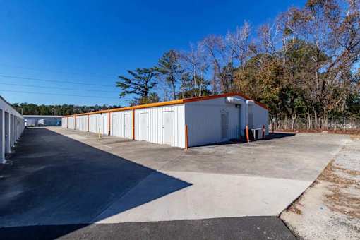 A long white building with orange trim is situated in a parking lot.