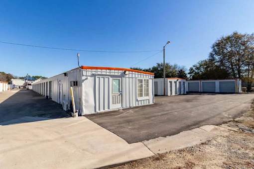 A long building with a red roof is situated in a parking lot.