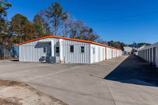 A long building with orange trim is surrounded by a parking lot.