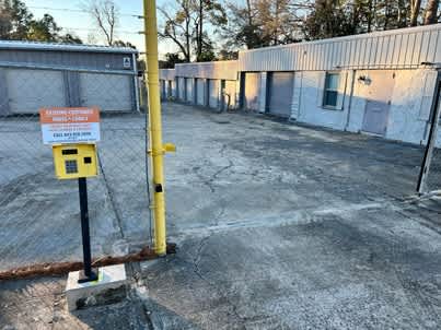 a parking lot in front of a building with a fence and a yellow parking meter