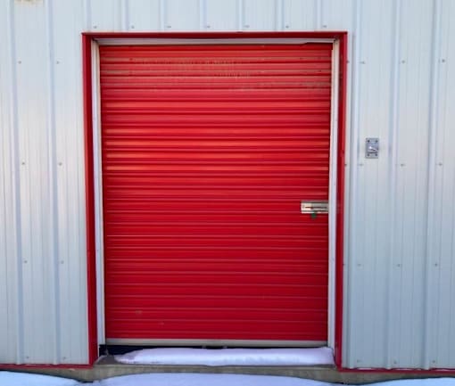 a red garage door in front of a white building