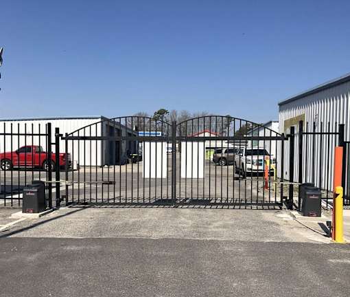 A black metal gate blocks the entrance to a parking lot.