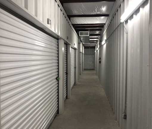 A long hallway in a storage unit with doors on both sides.