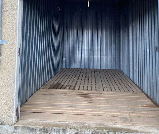 The image shows the interior of a storage unit with a wooden floor and metal walls.