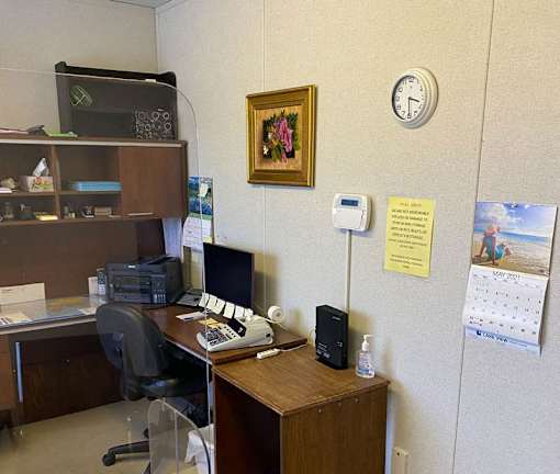 A small office with a desk, chair, and a clock on the wall.