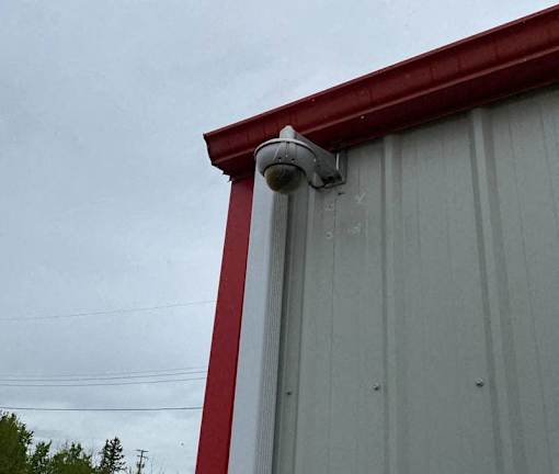 A grey building with a red trim and a security camera mounted on it.