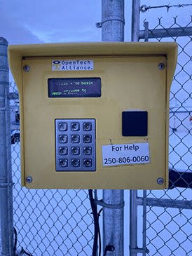 a yellow parking meter in front of a fence