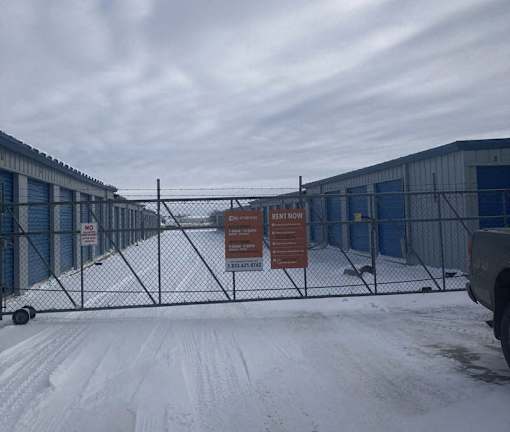 A snowy scene with a fence and a sign that says "NO PARKING ANY TIME".