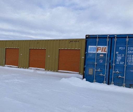 A blue shipping container with PIL written on it is in the snow.