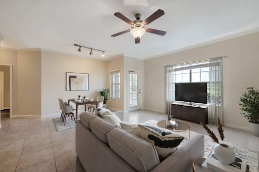A living room with a grey couch and a ceiling fan.