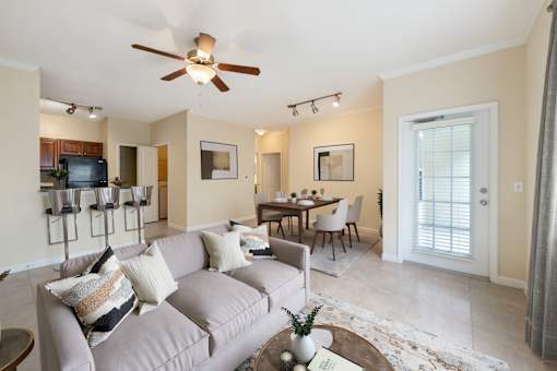 A living room with a grey couch and a ceiling fan.
