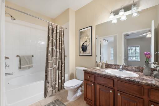 A bathroom with a white tub, a toilet, a sink, and a mirror.