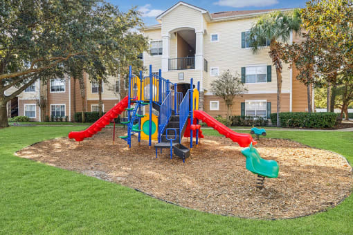 a playground with slides in front of an apartment building