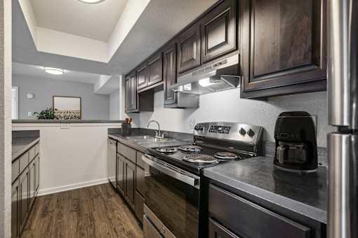 A modern kitchen with dark wood cabinets and stainless steel appliances.