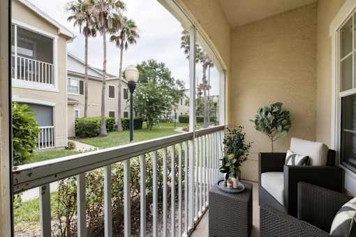 A balcony with a chair and a table with a plant on it.