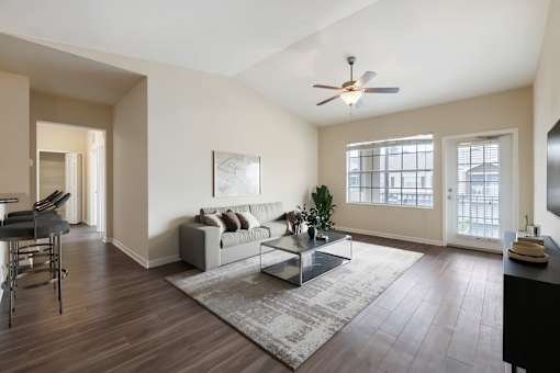 A living room with a couch, a coffee table, and a ceiling fan.