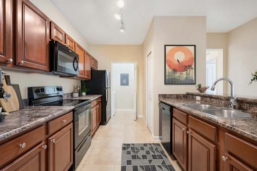 A kitchen with brown cabinets and a black refrigerator.
