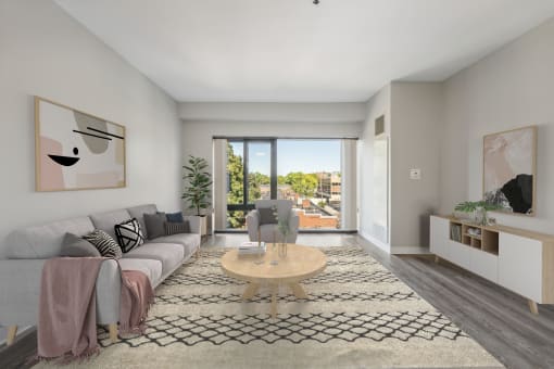 an open living room with a gray couch, a coffee table, and large windows at the Residences at Manchester Place in Manchester, New Hampshire