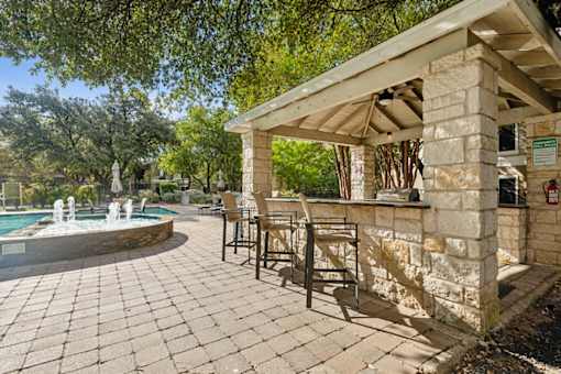 A pool area with a stone patio and a stone building.