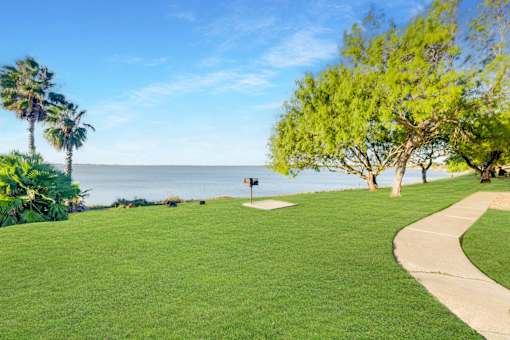 A green lawn with a pathway and a signpost at The Bay Club, Corpus Christi, TX, Texas, 78418