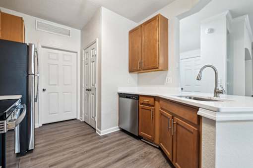 An open-concept apartment with updated lighting, stainless steel appliances, quartz countertops, vinyl plank wood style flooring and wooden cabinets.