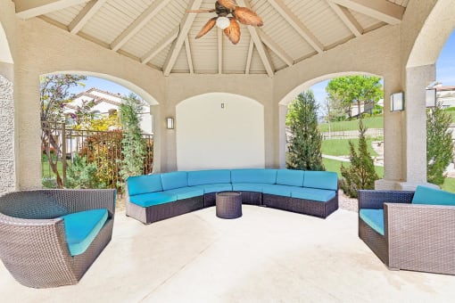 a covered patio with a blue couch and chairs at Altezza High Desert, Albuquerque, 87111