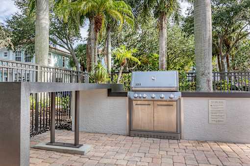A BBQ grill is in the middle of a brick patio.